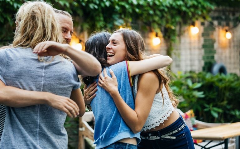 A Group Of Friends Embrace, Excited To See Each Other At Barbecue Meetup
