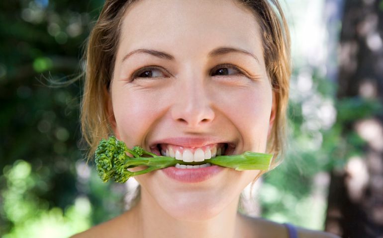 Woman biting into broccoli
