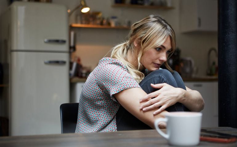 Portrait of pensive woman sitting at table in the kitchen