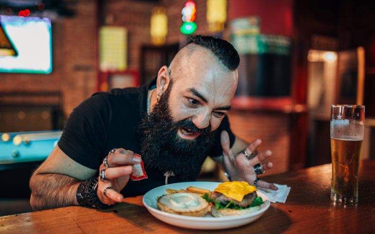Bearded man eating cheeseburger
