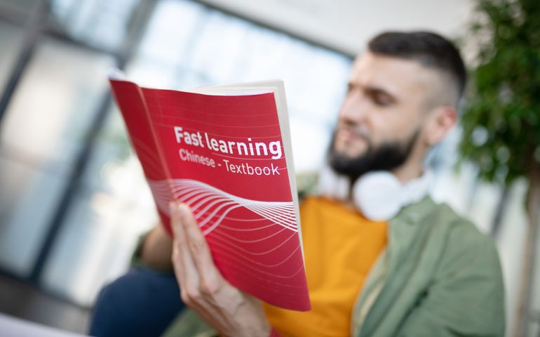 Bearded man learning Chinese language while reading book
