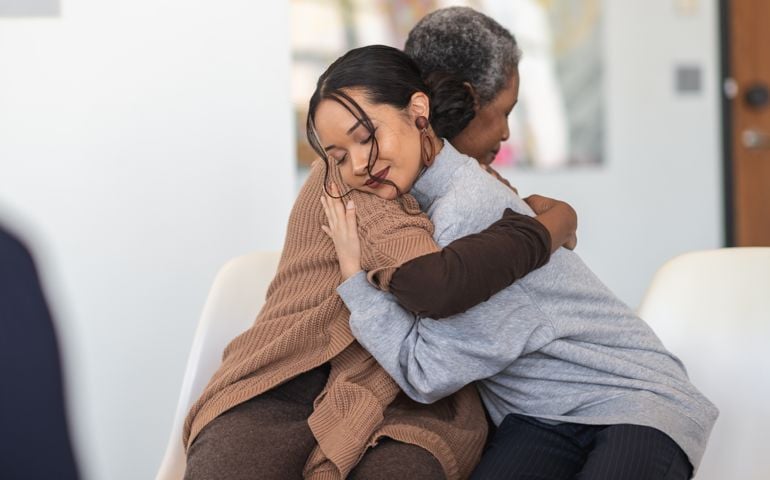 Supportive women hug while attending a group therapy session