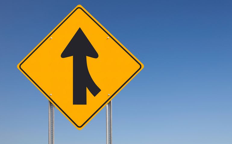 Merge Ahead Traffic Sign Post over Clear Blue Sky Background