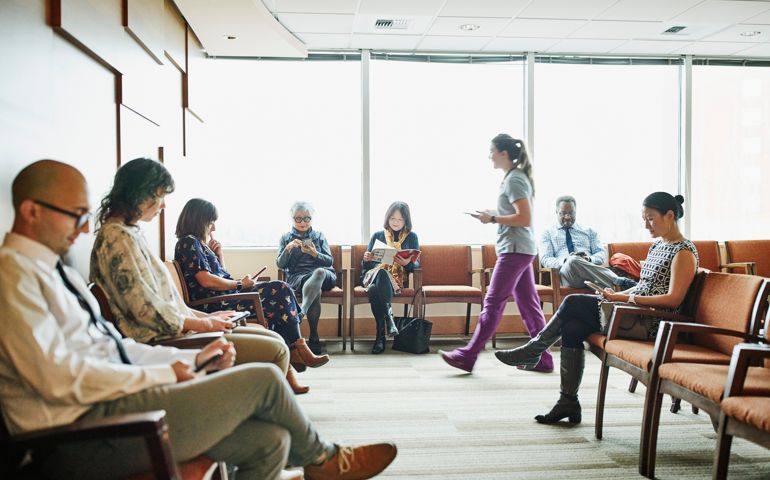 Nurse walking through medical office waiting room to greet patient