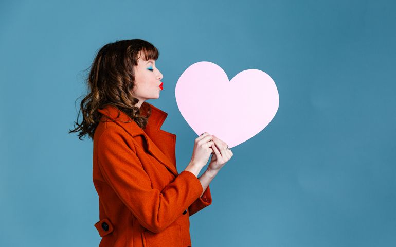 Young woman holding paper pink heart