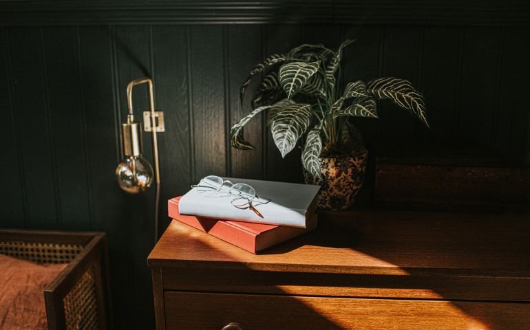 Reading glasses on two books stacked on a bedside table