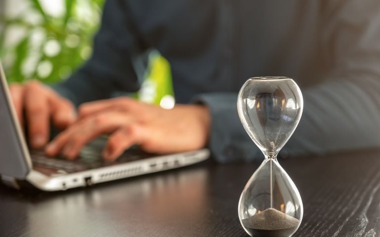 Hourglass with time running out in an office as a symbol of time pressure at work