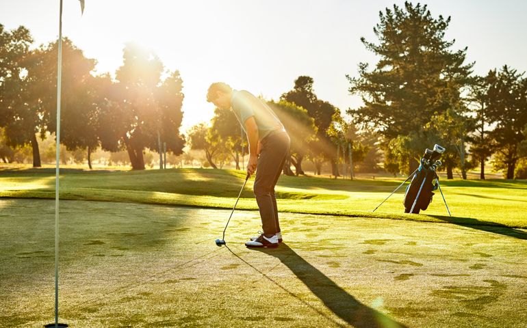 Male practicing golf on sunny day