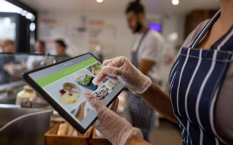 Close-up on a waitress using a tablet to take an order at a restaurant