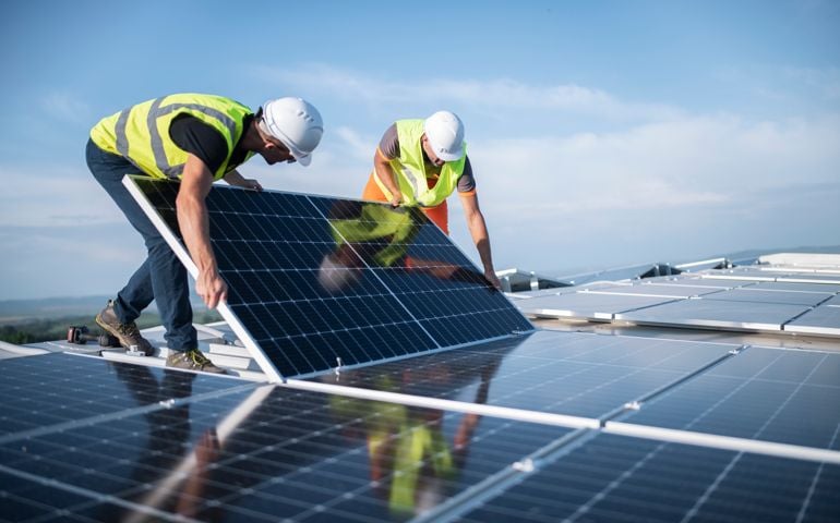 Two engineers installing solar panels on roof.