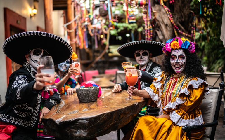 Portrait of friends doing a celebratory toast on the day of the dead at bar