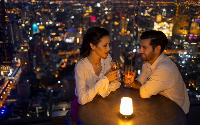 Caucasian couple celebrating holiday event at luxury rooftop bar at night.