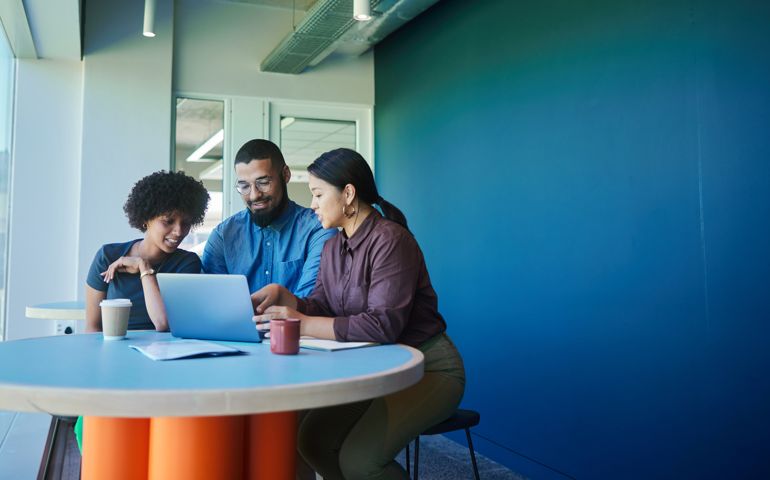 Smiling young businesspeople working together on a laptop in an office