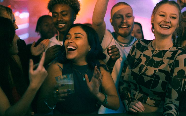 Cheerful female and male friends dancing while celebrating weekend party in club