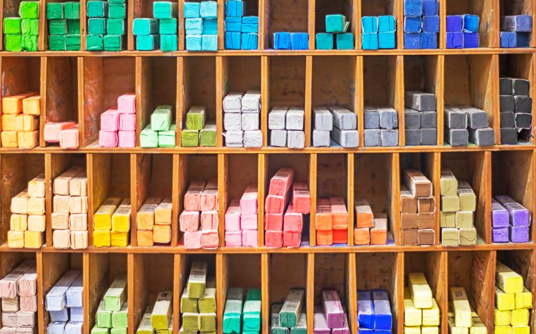 multi-colored dry pastel crayons laid out on shelves
