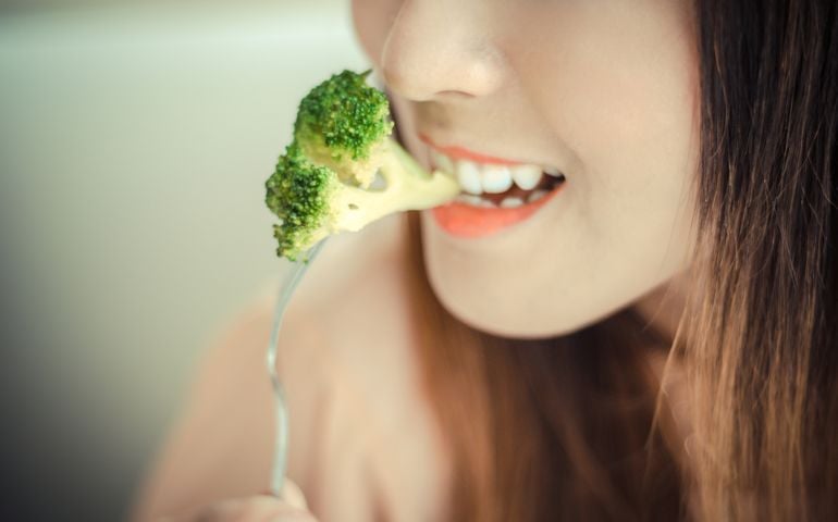 happy smiling woman eating broccoli