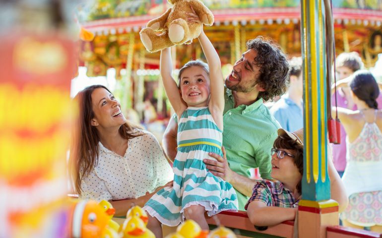 Girl holding teddy bear as trophy in fishing game in amusement park