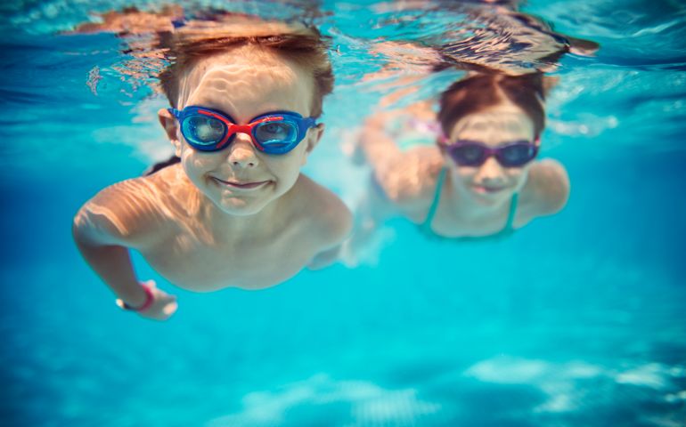 Happy kids swimming underwater in pool