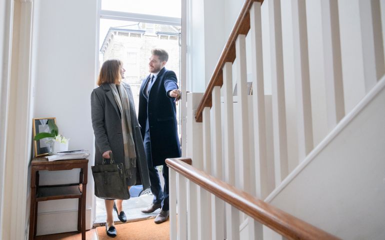 Mid adult couple arriving home after work and entering hallway