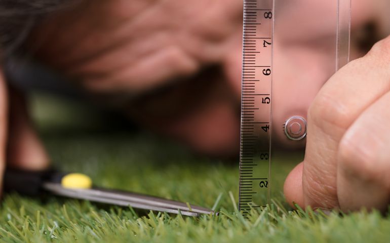 Man Using Measuring Scale While Cutting Grass