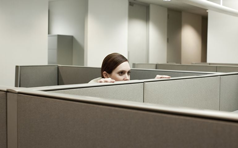 Woman hiding behind cubicle in office