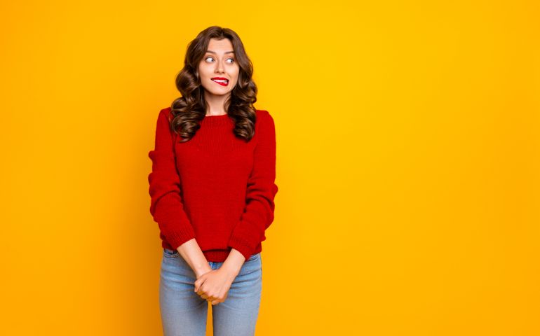 Photo of pretty curly wavy charming cute cheerful nice good girlfriend standing hesitating and shy looking away at something with hands folded isolated over yellow vivid color background