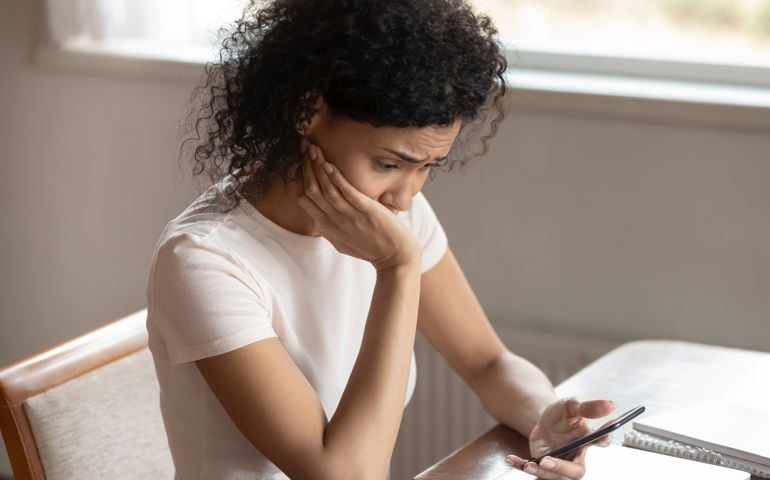 Frustrated biracial woman having operational cellphone problems