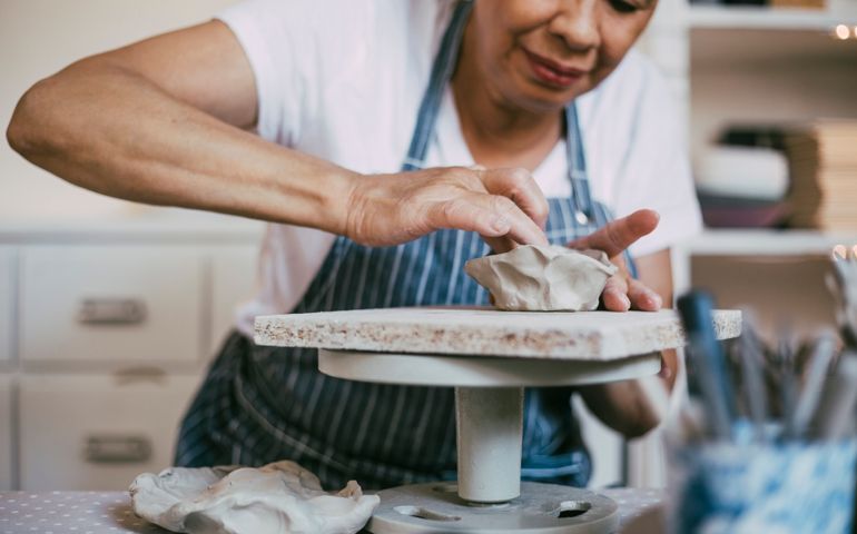 Senior woman kneading clay in bowl shape at workshop