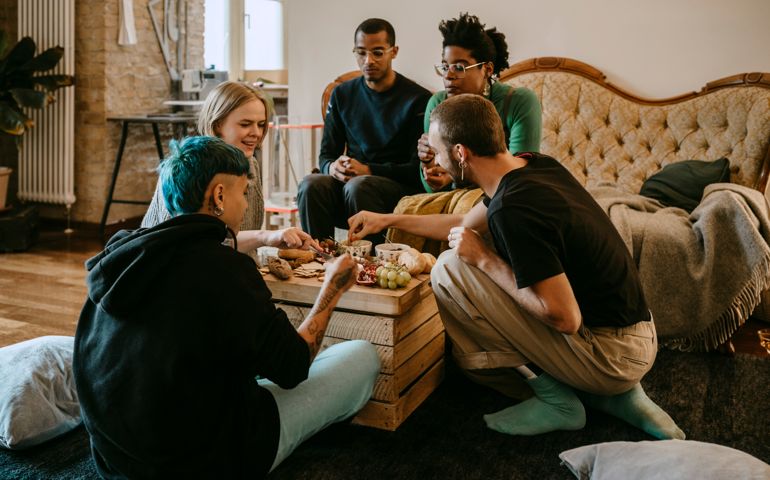 Female and male friends having breakfast in living room at home
