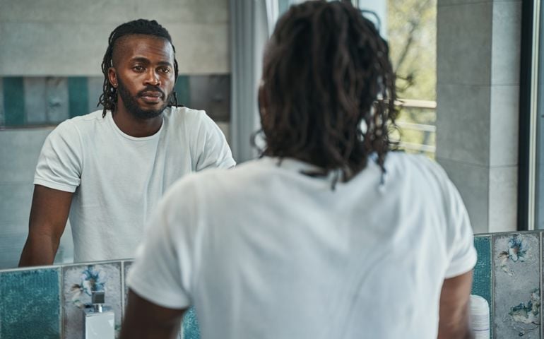 Calm male concentrated on examining his face in bathroom