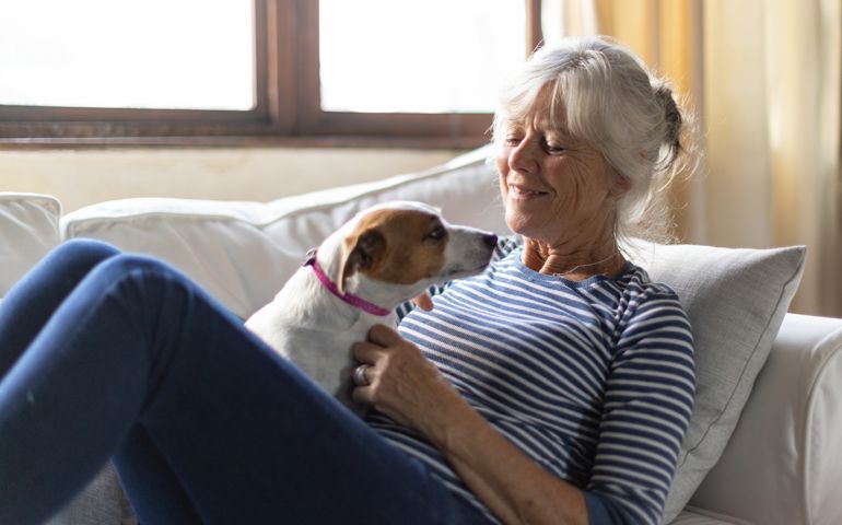 Senior woman playing with pet dog at home