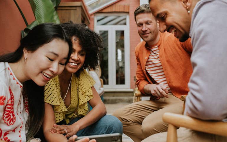 A group of 4 young people watch a video on a smart phone