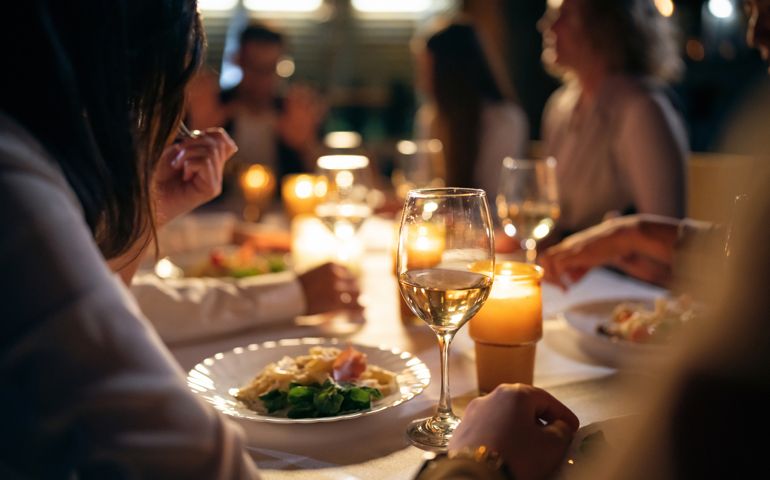 Unrecognizable multiracial female and male friends, having the dinner at the restaurant balcony