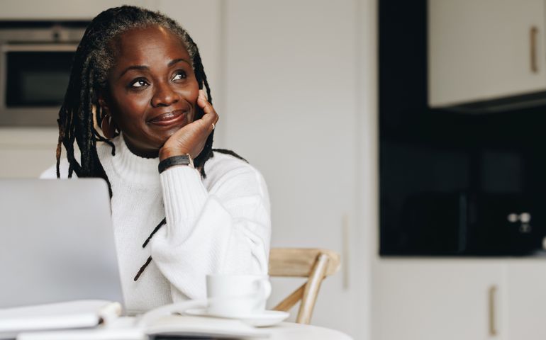 Mature businesswoman looking away thoughtfully in her home office