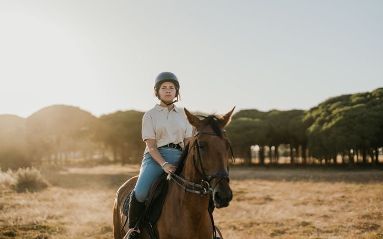 backlit photo of a young rider riding a horse