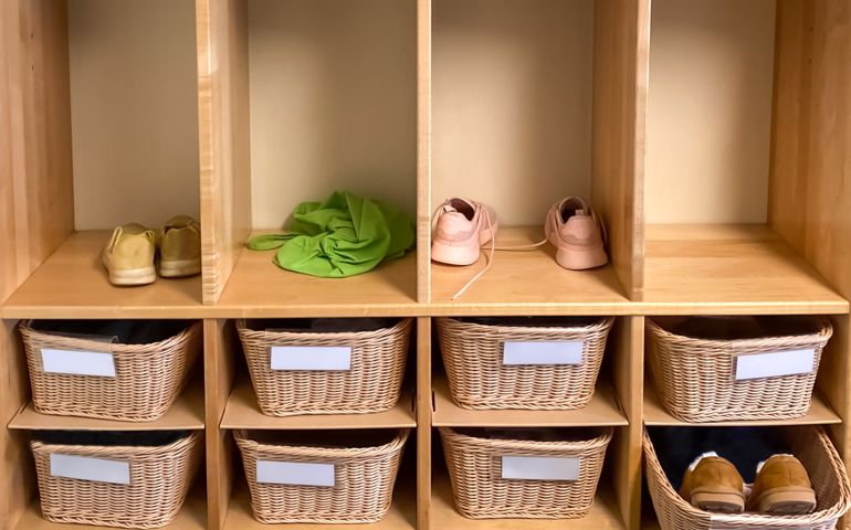 wicker basket storage cubbies &amp; closets in preschool classroom with various belongings in view