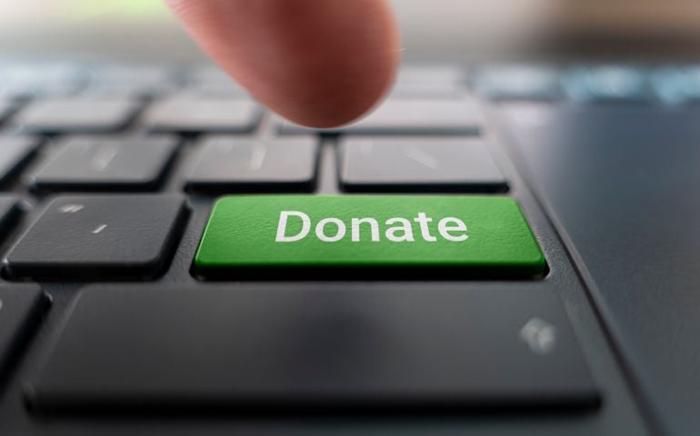 Red donate button on keyboard close-up. blurred in motion background.