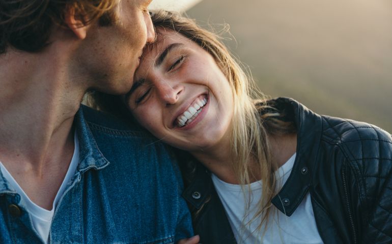 Romantic boyfriend kissing on happy girlfriend's forehead