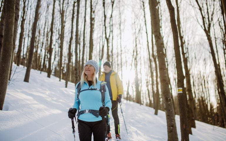 Senior couple hiking in winter forest.