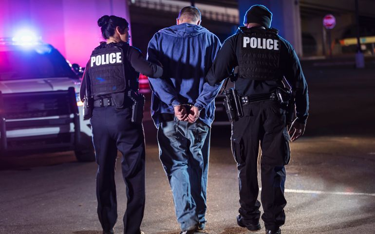Handcuffed suspect being arrested by police at night