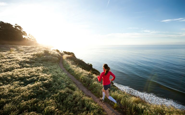 Woman trail running near the ocean.
