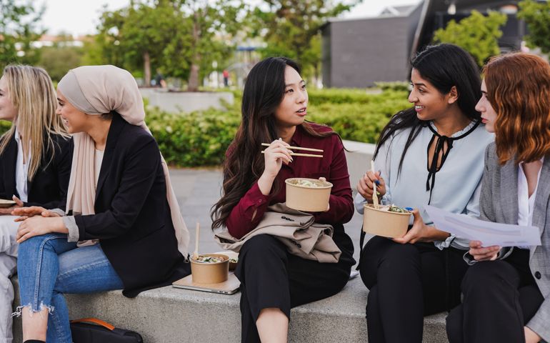 Young diverse business women having fun together during lunch break outside of office
