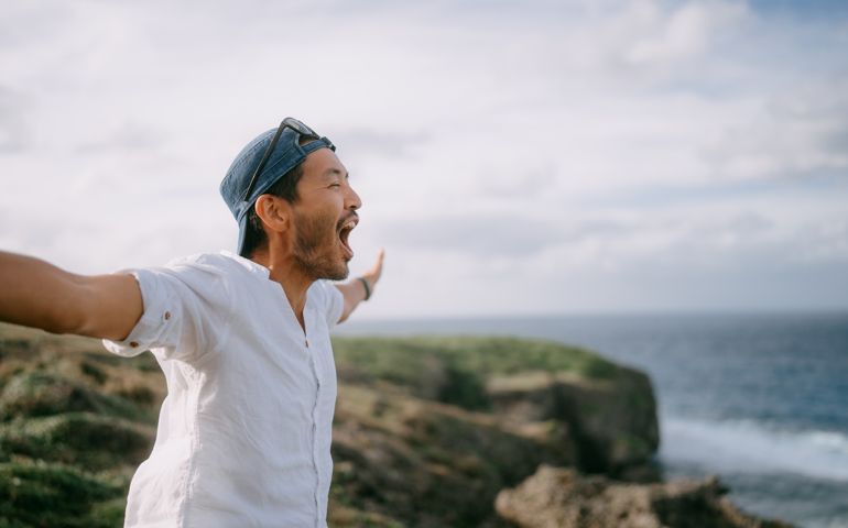 Man shouting on top of cliff by sea