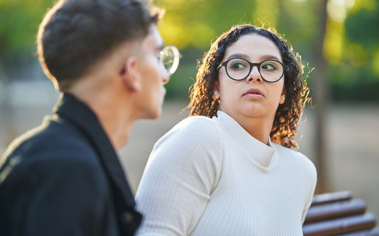 Woman keeping distance and rejecting a man while having a date together in a park.
