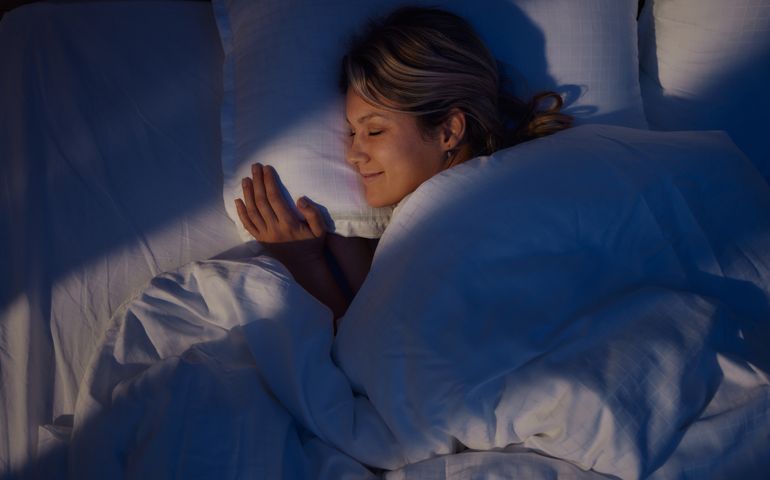 Above view of smiling woman sleeping in bed.