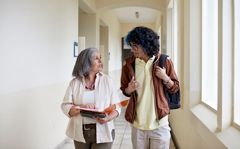 Student and professor walking and talking on campus
