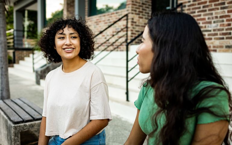 Two women sitting on the bench and talking