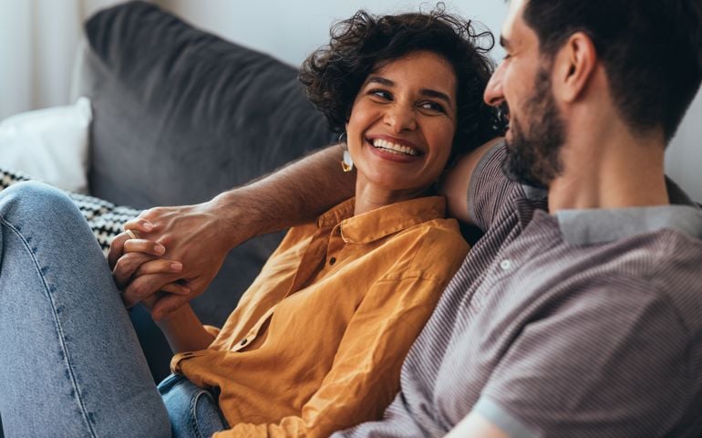 A Happy Beautiful Couple Sitting On The Cozy Sofa At Home And Relaxing