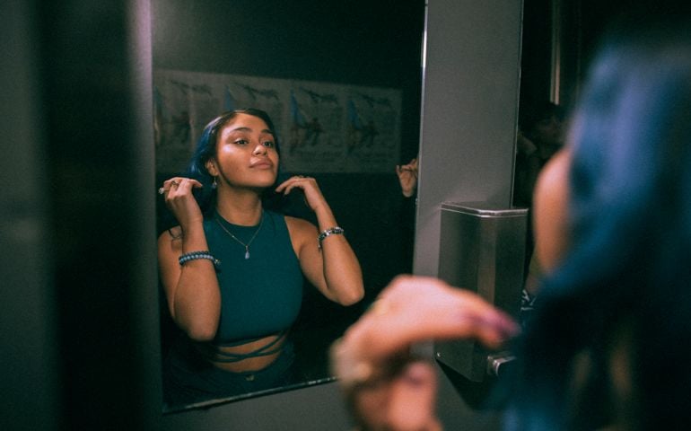 Reflection of young woman looking at mirror reflection