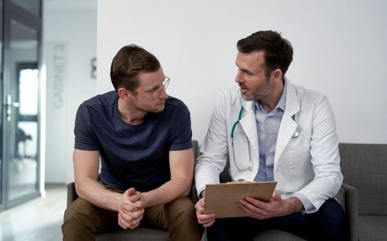 Mature doctor discussing with man at clinic